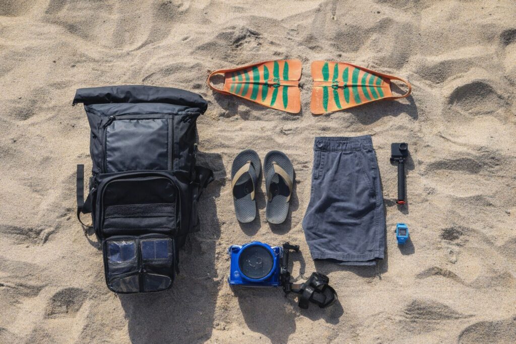 Reseutrustning och strandprylar utlagda på sand.